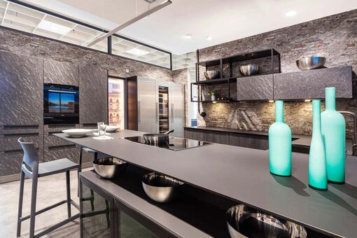 Die dünne Arbeitsplatte in dieser modernen, grauen Küche lässt das großzügige Kochfeld fast frei im Raum schweben.