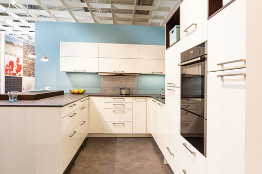 Das klassische Design der Küche mit weißen Lackfronten steht in schönem Kontrast zur farbenfrohen Wandgestaltung